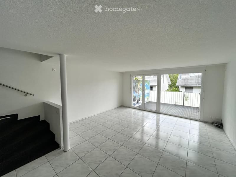 Empty hallway with tiled floor, white walls, and a sliding glass door leading to an outdoor area.