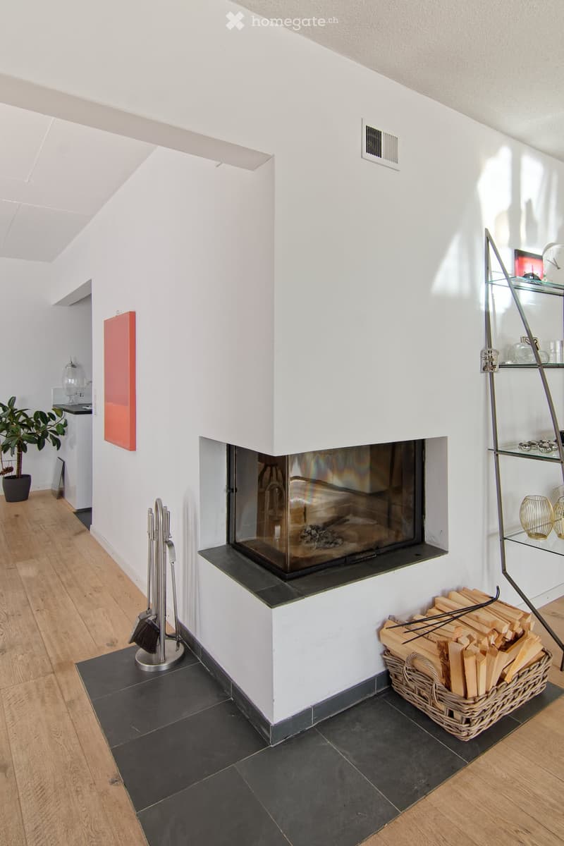 Modern living room with a sleek fireplace, wooden flooring, and a basket of firewood nearby.