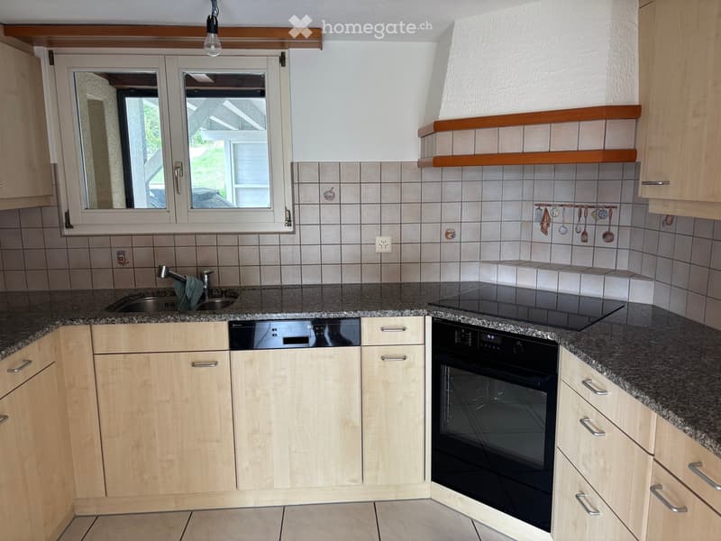 Modern kitchen with light wooden cabinets, granite countertop, stainless steel sink, electric stove, and built-in oven and dishwasher.