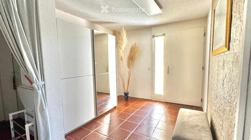 Hallway with a large mirror cabinet, a small bench, a vase with dried plants, and a curtain on the left side.