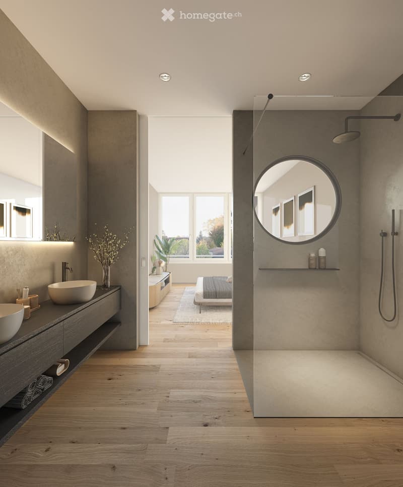Modern bathroom with a sleek sink, round mirror, and shower area. The space features wooden flooring, built-in storage, and a small bedroom visible through an open doorway.
