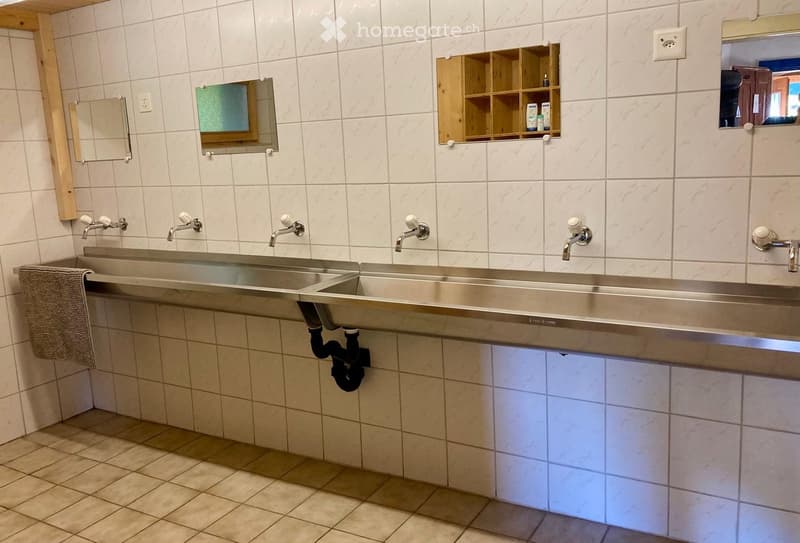 Bathroom with multiple sinks, mirrors, wooden shelves, and a towel on the side.