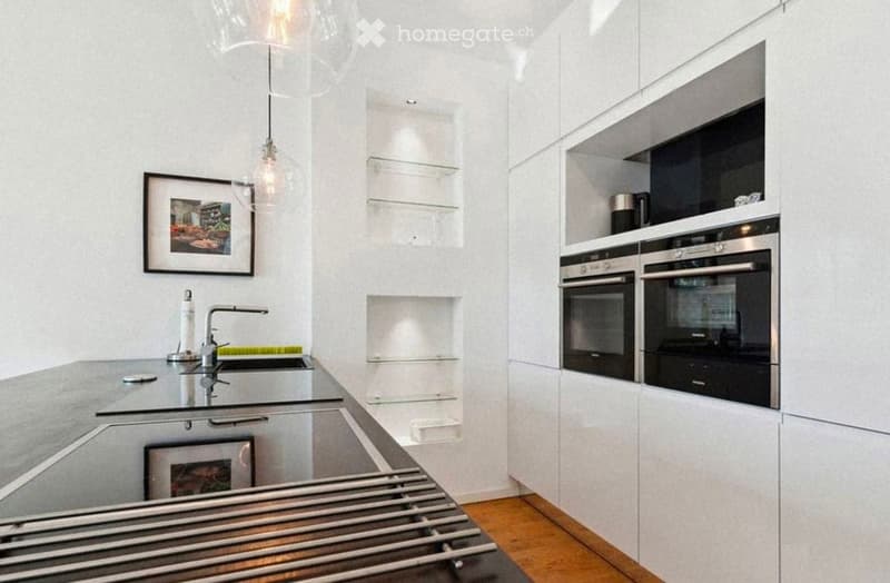 Modern kitchen with white cabinets, stainless steel appliances, a central island with a sink, and pendant lighting.