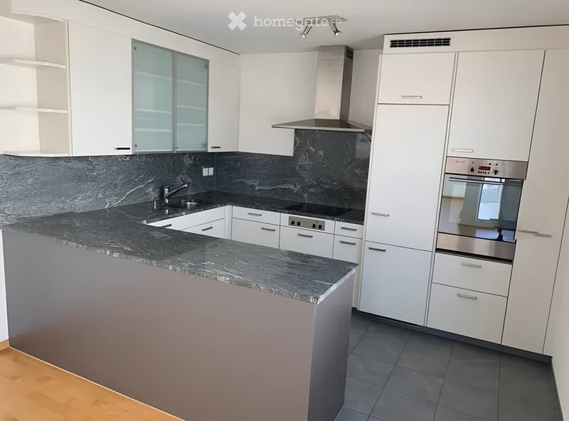 Modern kitchen with white cabinets, granite countertops, stainless steel appliances, and a central island.