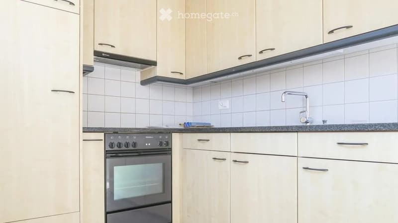 Modern kitchen with white cabinets, tiled backsplash, and stainless steel oven and faucet.