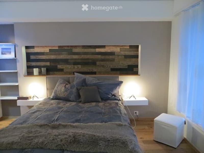 Modern bedroom with a large bed, wooden headboard, nightstands, and a fur throw on the bed.