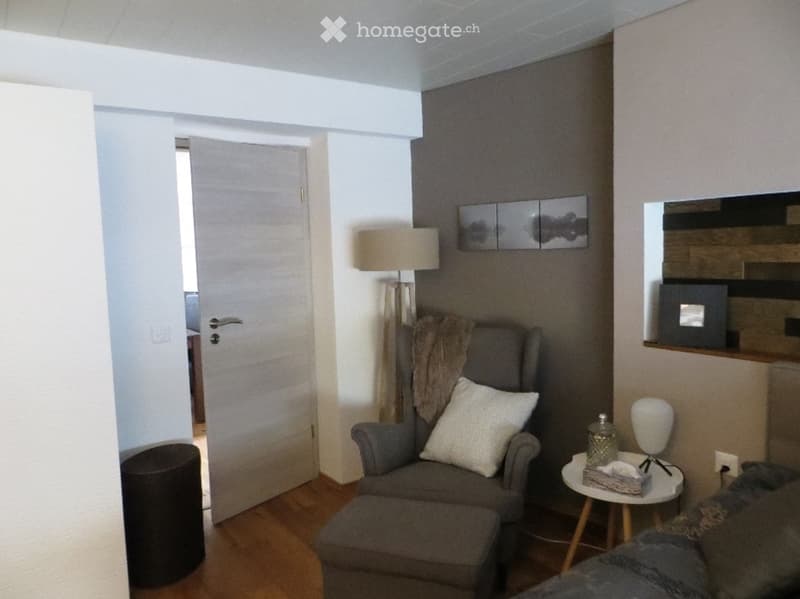 Cozy living room with grey sofa, ottoman, coffee table, floor lamp, and decorative items.