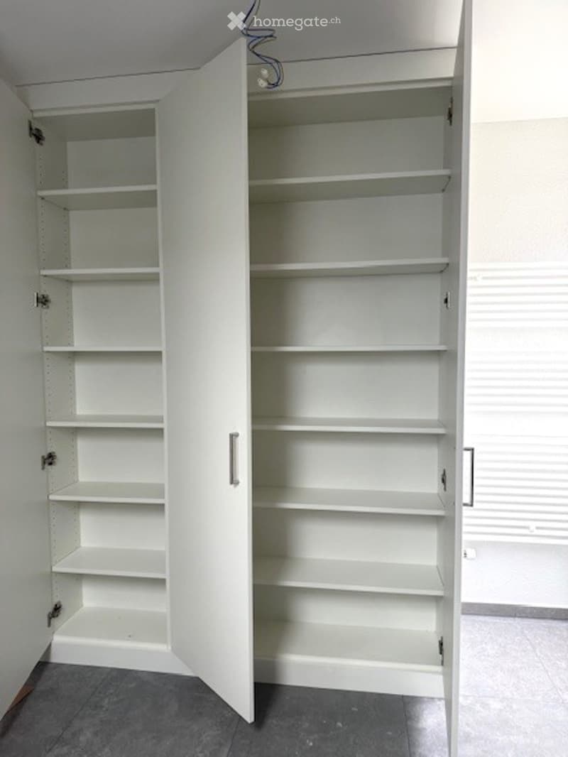 Empty white wardrobe with doors open and many shelves