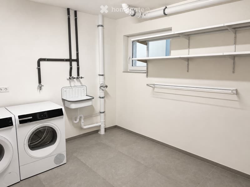Clean, modern bathroom with a washing machine, sink, shelves, and a rod for hanging items.