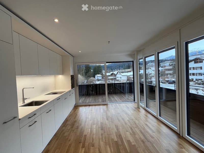 Modern kitchen with white cabinets, a sink, and large windows offering a scenic mountain view.