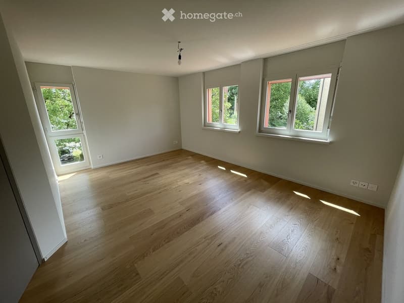 Empty room with wooden flooring, white walls, and multiple windows allowing natural light. No furniture or equipment present.