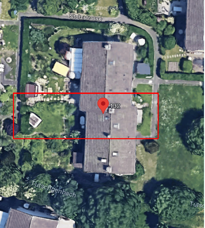 Aerial view of a large, rectangular building with a flat roof, surrounded by greenery and trees. The building is located near a road named Stolzstrasse and Tutscherbach.