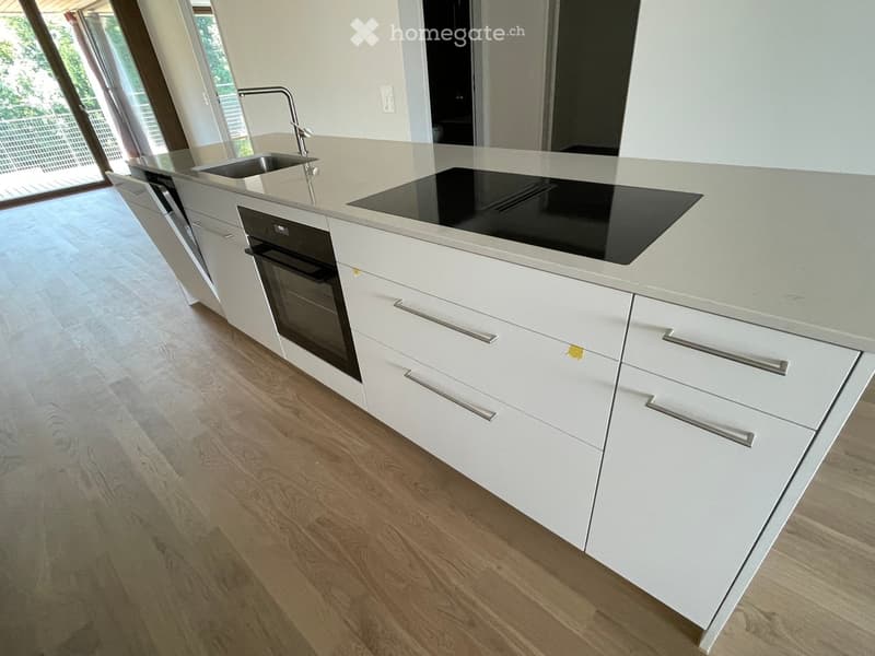 Modern kitchen with white cabinets, a central island, an induction cooktop, and a sink with a modern faucet.
