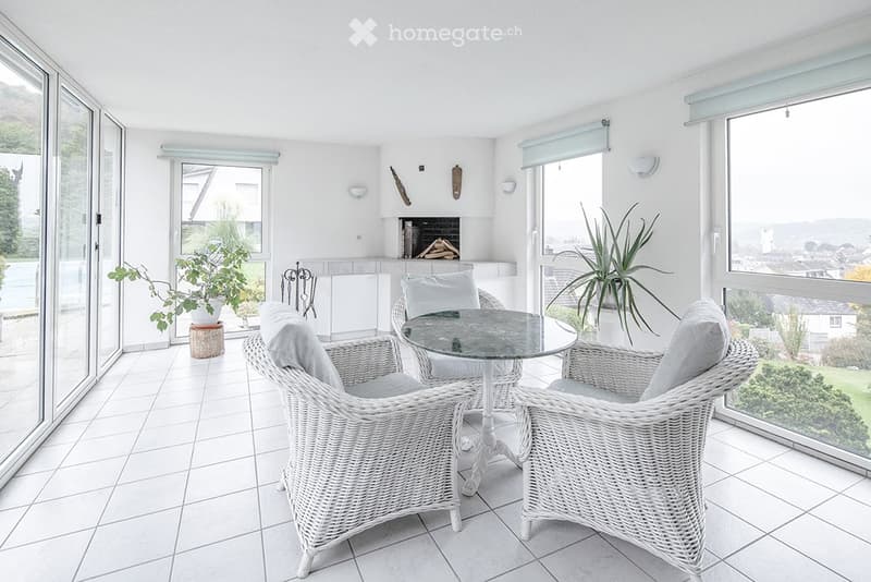 white wicker chairs, table, white tiles, fireplace, potted plants, sliding glass doors, glass windows, view
