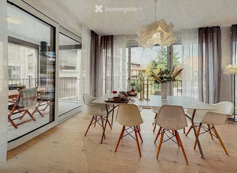 Dining area with a glass table, six chairs, a vase with flowers, and candles on the table. Large windows and a view of the balcony.