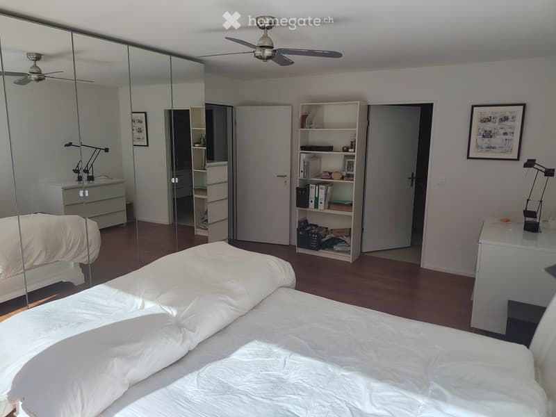 Modern bedroom with a large bed, mirrored wardrobe, shelves, and lamps.