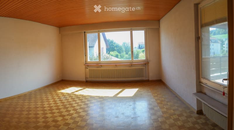 Empty room with wooden checkered flooring, white walls, large windows, and radiators. No furniture or personal items present.