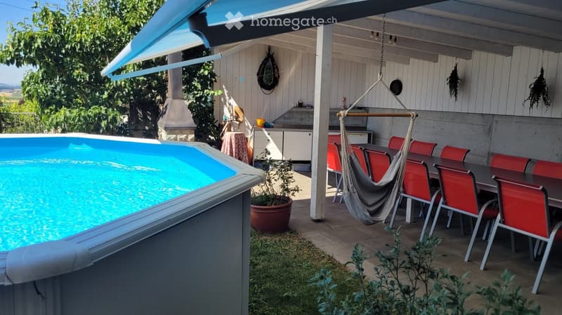 Outdoor area with a swimming pool, patio furniture, and a covered seating area with a hammock and dining table.