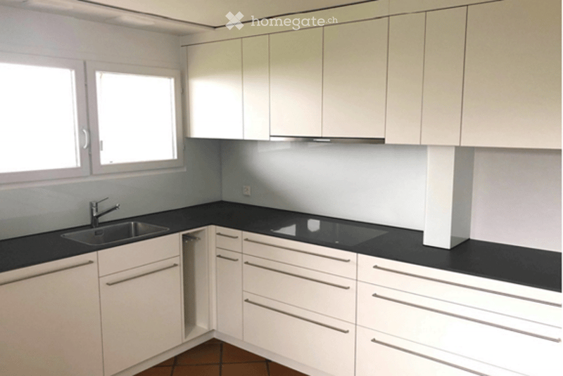 Modern kitchen with white cabinets, black countertops, and a stainless steel sink.