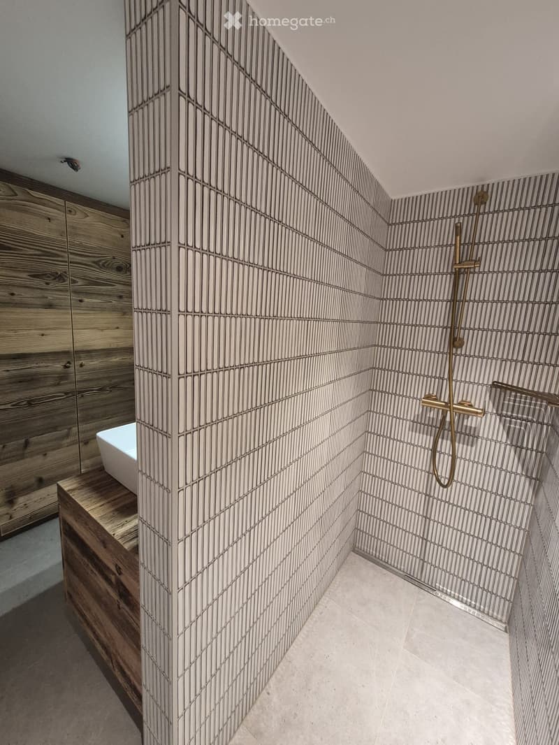Modern bathroom with wooden cabinetry, a bathtub, and a shower area with a sleek, geometric tile design.