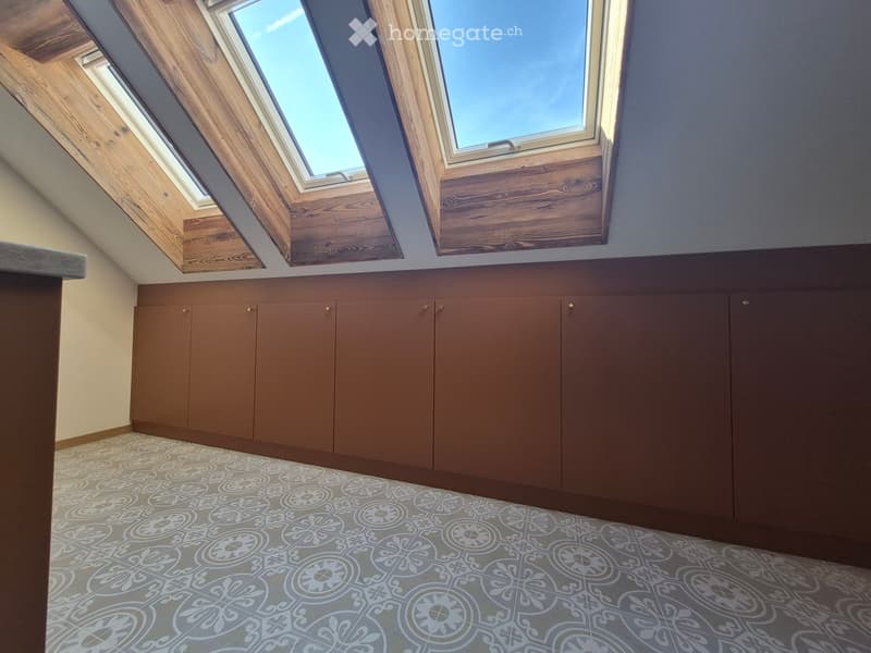 An attic space with wooden cabinets, skylight windows, and patterned tile flooring.