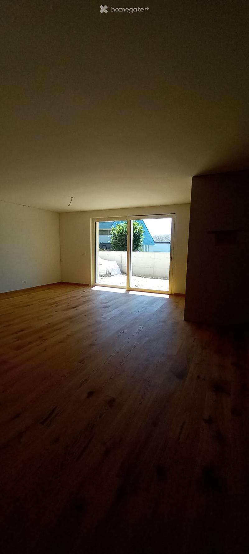 Empty room with wooden flooring and large sliding glass doors leading to an outdoor area.