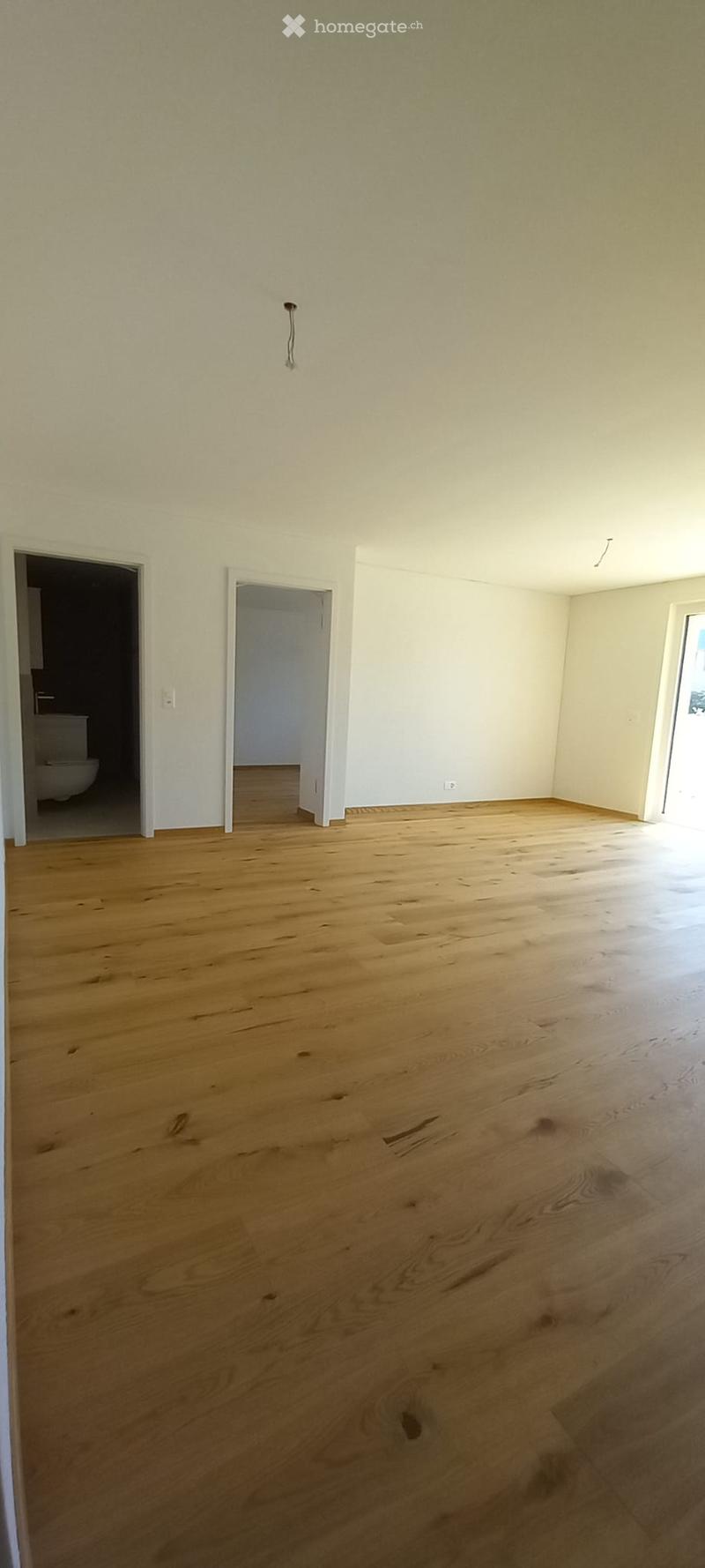 Empty room with wooden flooring and white walls, featuring two doorways leading to other rooms.