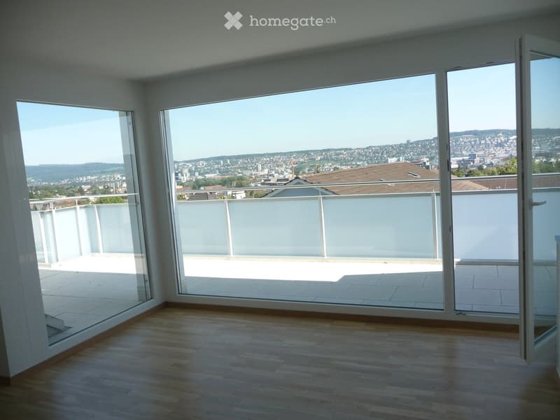Empty room with wooden flooring and large glass doors opening to a balcony with a city view.