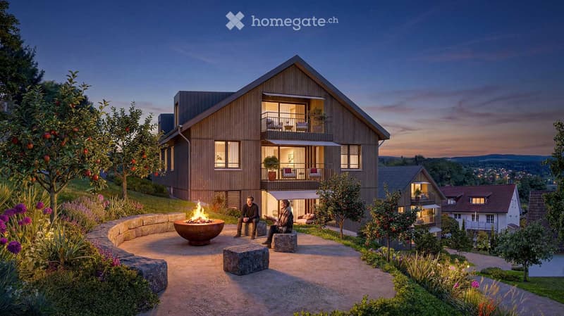 Modern two-story house with wooden facade, large windows, and balconies, surrounded by a landscaped garden with a fire pit and seating area.