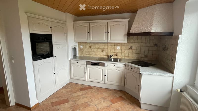 Bright kitchen with white cabinets, stainless steel appliances, and tiled backsplash.