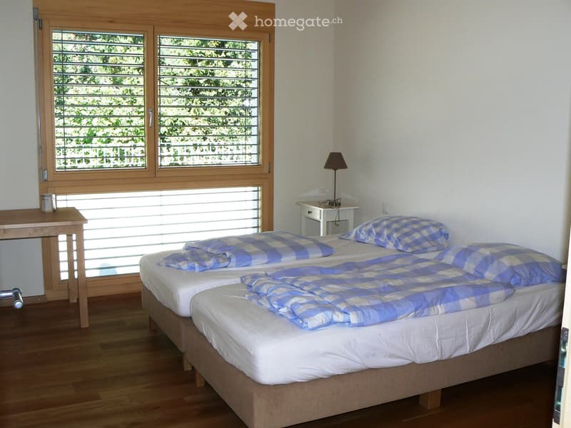 bedroom with two single beds, nightstand, desk, and window