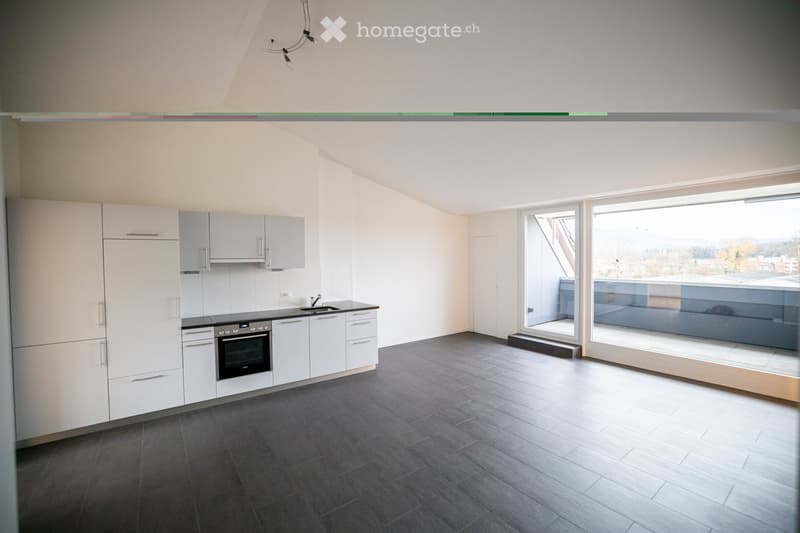 Modern kitchen with white cabinets, dark tiled floor, and large windows offering a view of the outside area.