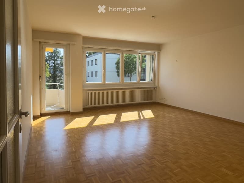 Empty room with wooden flooring, large windows, and a radiator. No furniture or equipment present.
