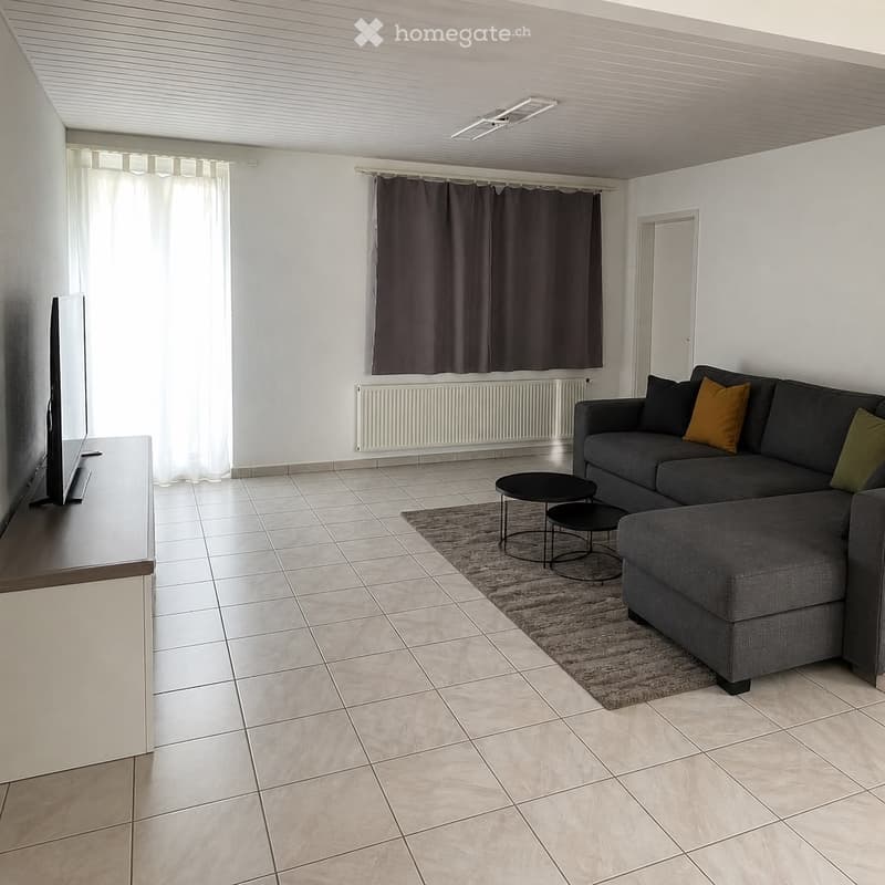 Modern living room with tiled flooring, grey sectional sofa, coffee table, TV stand, radiator, and curtains.