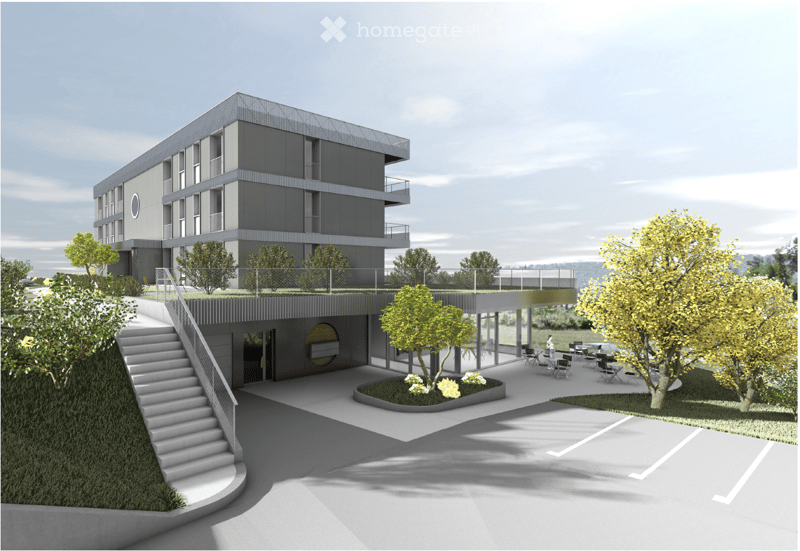 Modern multi-story building with a raised ground floor, outdoor seating area, and parking lot.