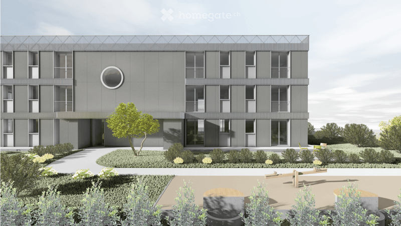 Modern multi-story building with grey facade, large windows, and a circular skylight. The surrounding area includes a landscaped garden with shrubs, a tree, and a small seating area with a bench and chairs.