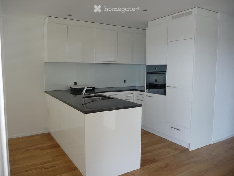 Modern kitchen with white cabinets, black countertop, and stainless steel sink and faucet.