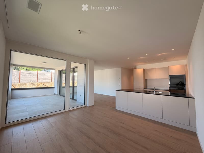 Modern kitchen with white cabinets, a black countertop, and a sink, connected to a tiled patio through large glass doors.