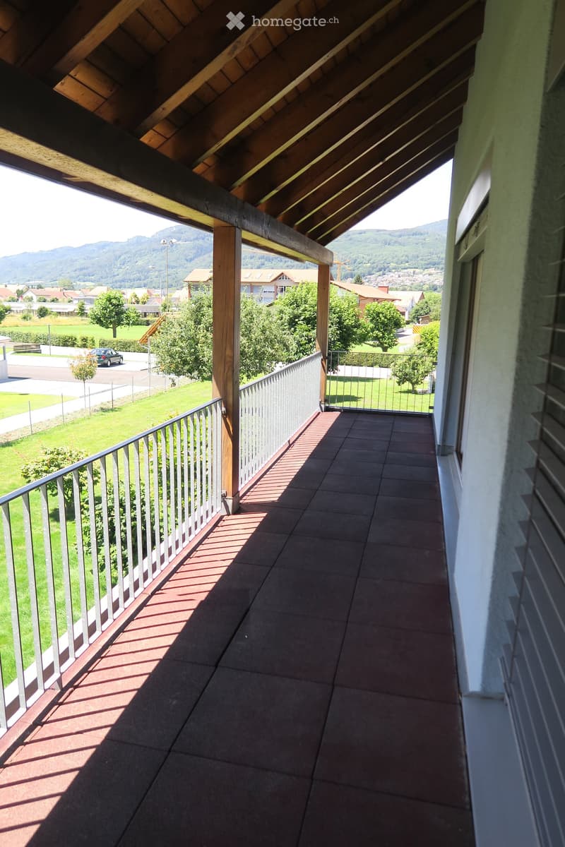 Balcony with tiled floor, wooden beams, metal railing, and scenic mountain view.