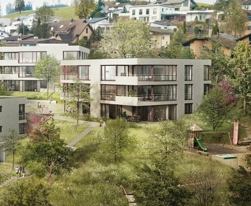 A modern multi-story residential building with large windows and balconies, surrounded by greenery and a playground area.