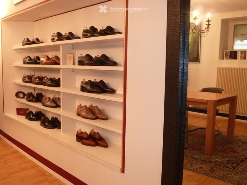 A well-organized shoe storage area with multiple shelves filled with various pairs of shoes, a small table, and a chair in the background.