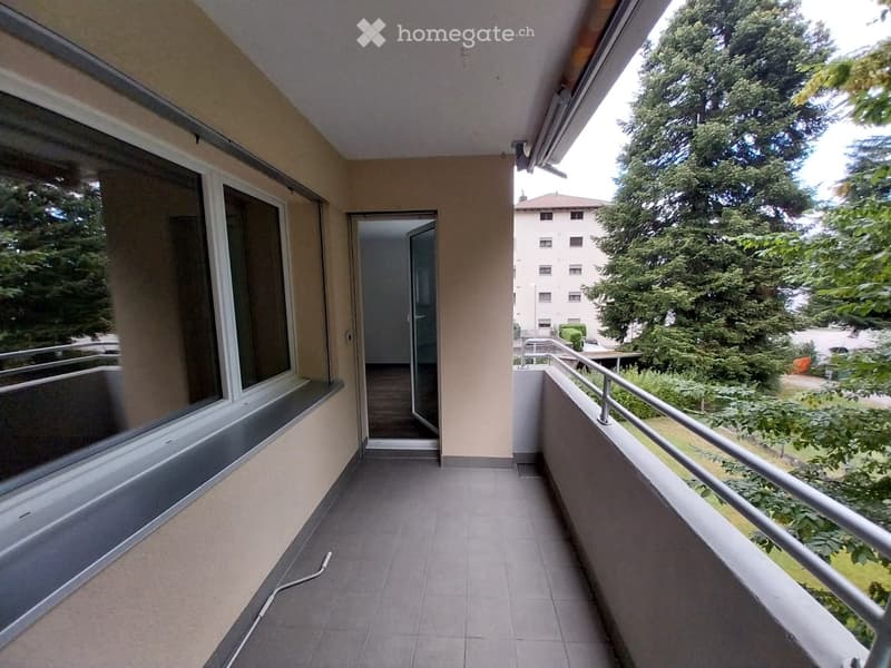 Balcony with tiled floor, metal railing, large windows, and access to an interior space.