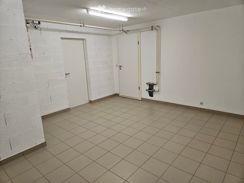 Empty room with tiled floor, white walls, two doors, and exposed pipes and electrical fixtures.