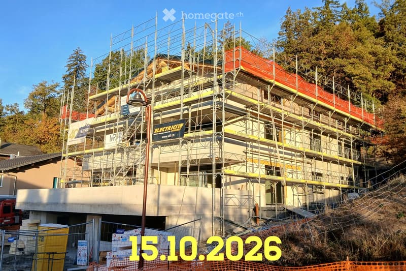 A multi-story building under construction, covered in scaffolding with visible signage and a partially constructed facade.