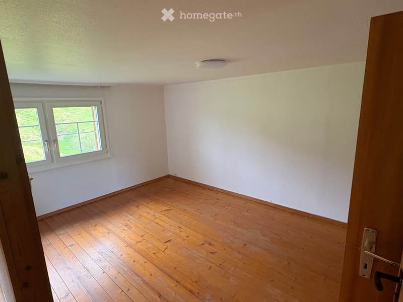 Empty room with wooden flooring, white walls, and a single window with white frame and glass panes.