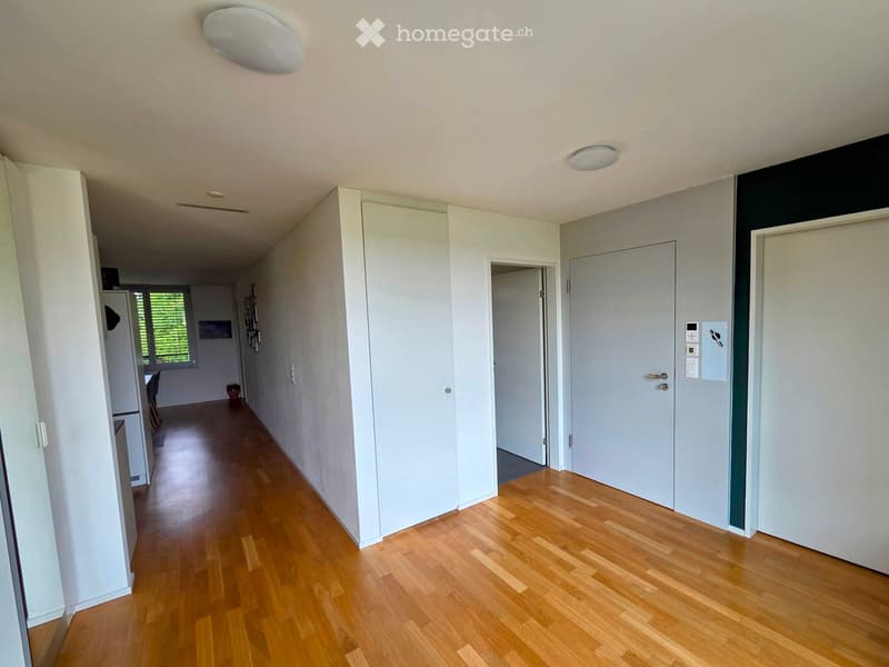 Empty hallway with wooden flooring, white walls, and several doors leading to other rooms.