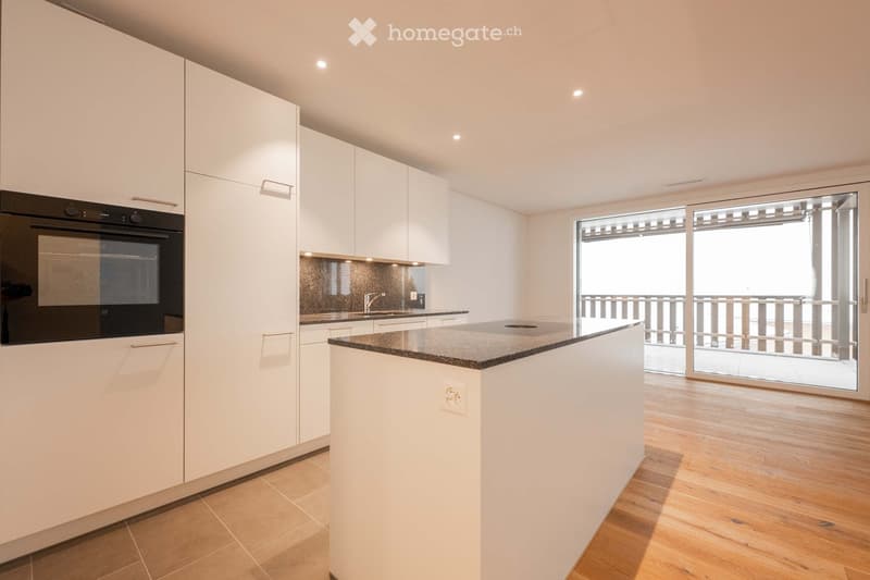 modern kitchen with white cabinets, black oven, granite countertop, island with power outlet, sliding glass door to balcony