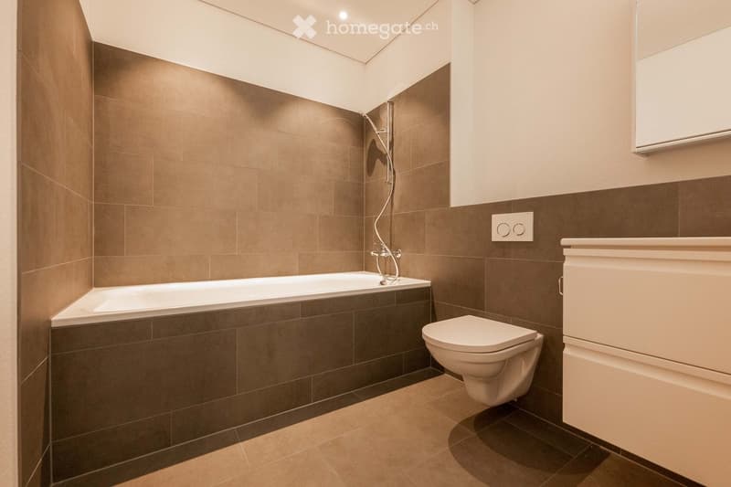 Bathroom with bathtub, toilet, and shower, tiled walls and floor, white fixtures