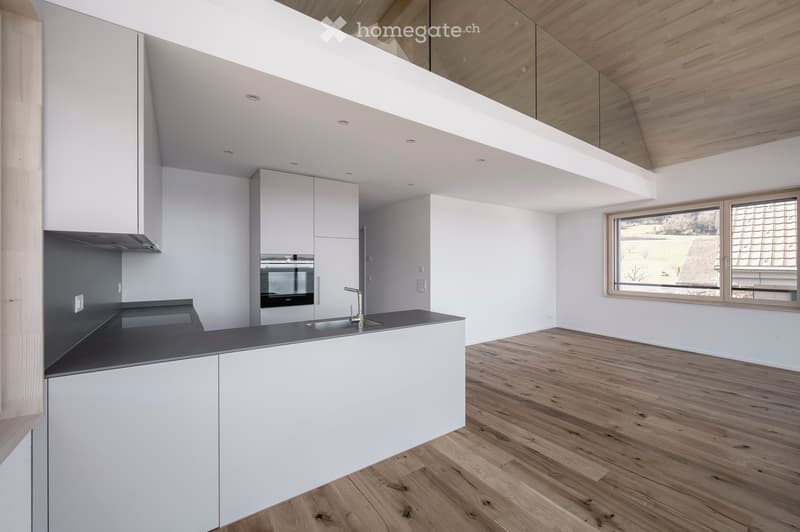 Modern kitchen with white cabinets, dark countertop, and wooden flooring. Features a sink, faucet, and built-in oven.