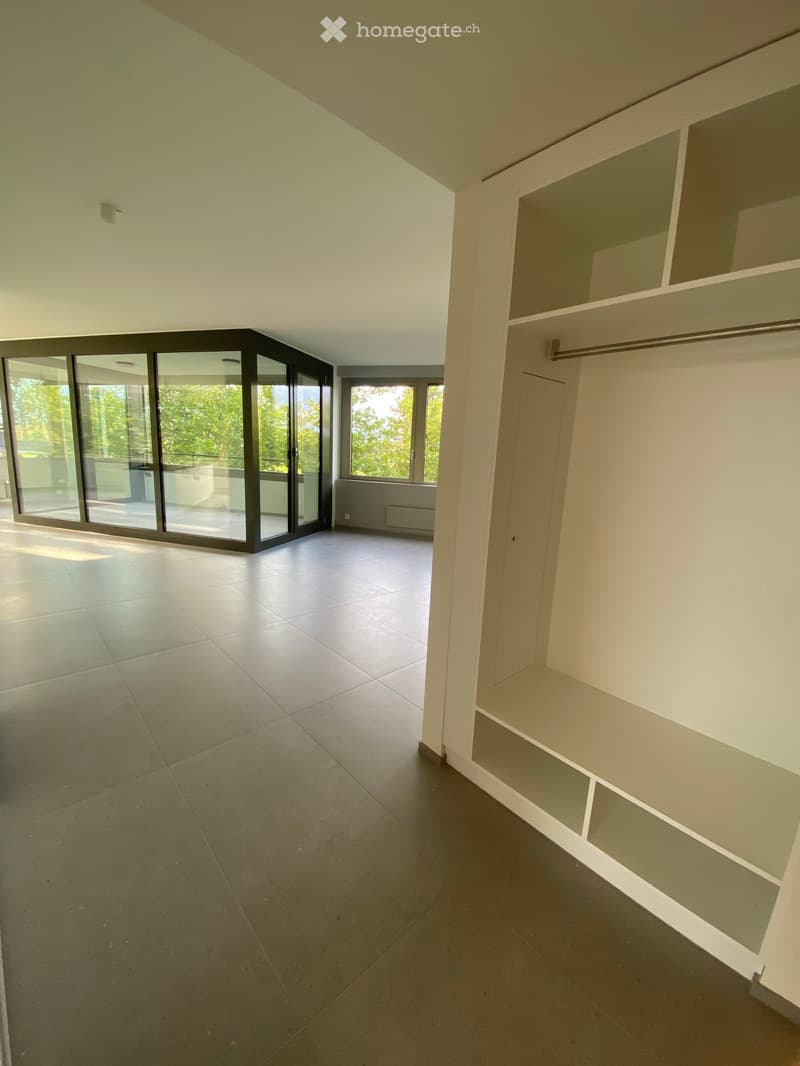 Empty room with large sliding glass doors leading to a balcony, white walls, and a built-in closet with open shelving.